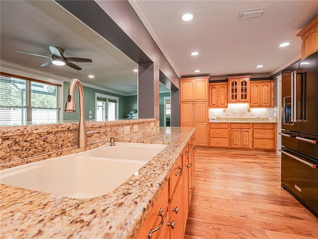 kitchen featuring tasteful backsplash, crown molding, visible vents, a sink, and high quality fridge