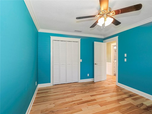 unfurnished bedroom with crown molding, visible vents, a closet, and light wood-style floors