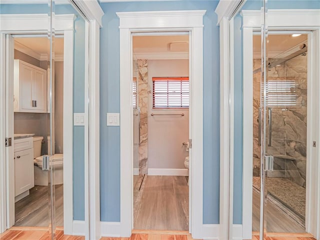 hallway with light wood-style flooring, crown molding, and baseboards