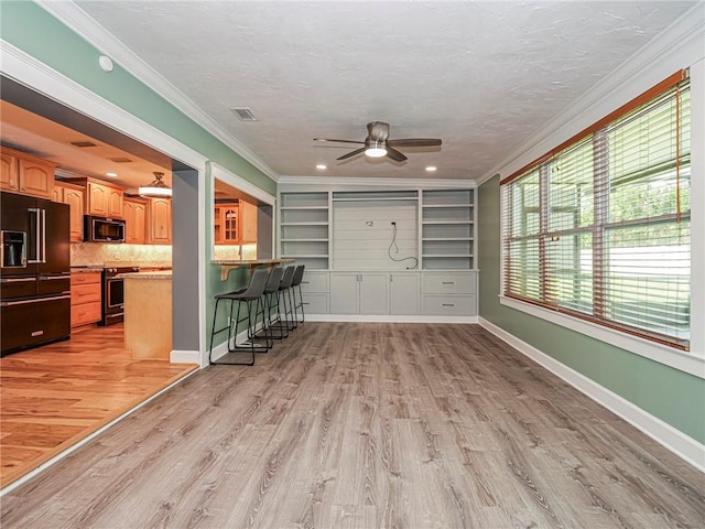 unfurnished living room with baseboards, light wood-type flooring, a ceiling fan, a textured ceiling, and crown molding