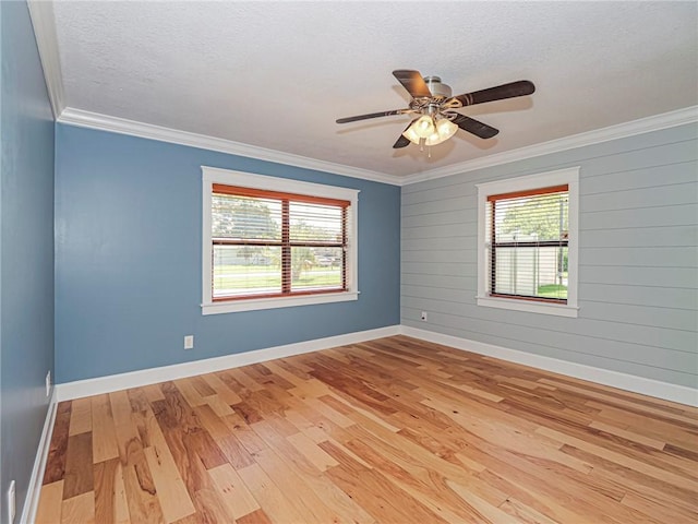 empty room featuring ornamental molding, baseboards, light wood-type flooring, and a textured ceiling