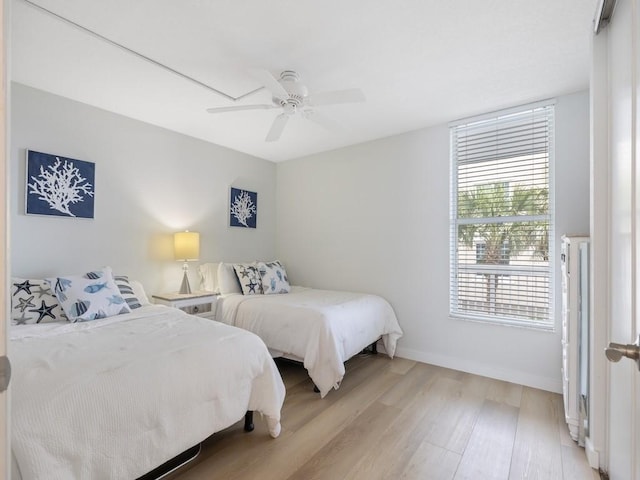 bedroom with baseboards, a ceiling fan, and light wood-type flooring
