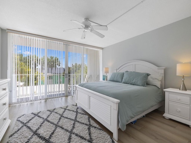 bedroom featuring access to outside, ceiling fan, floor to ceiling windows, and wood finished floors