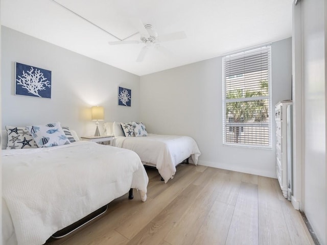 bedroom with baseboards, ceiling fan, and light wood-style flooring