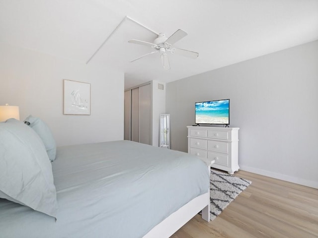 bedroom with light wood finished floors, a closet, visible vents, baseboards, and ceiling fan
