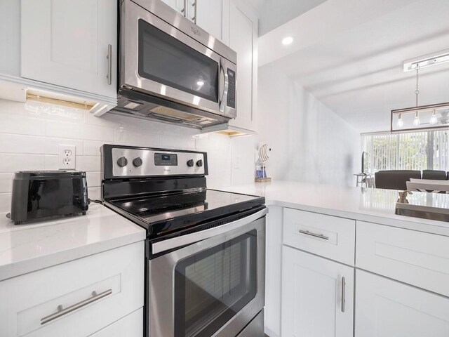 kitchen with backsplash, stainless steel appliances, white cabinetry, and light countertops