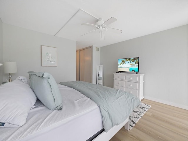 bedroom featuring a ceiling fan, visible vents, baseboards, a closet, and light wood-style flooring
