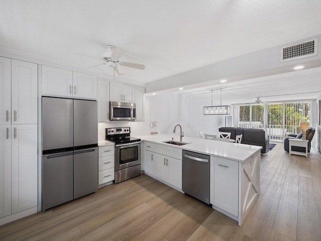 kitchen with a sink, a peninsula, visible vents, a ceiling fan, and appliances with stainless steel finishes