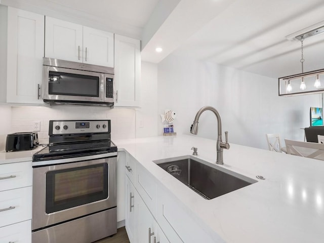 kitchen featuring appliances with stainless steel finishes, a sink, light countertops, white cabinetry, and decorative backsplash