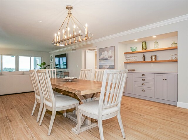 dining area featuring light hardwood / wood-style flooring, a notable chandelier, and crown molding