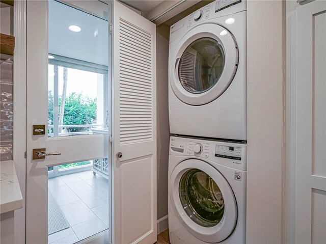 laundry area with light tile patterned floors and stacked washer and clothes dryer