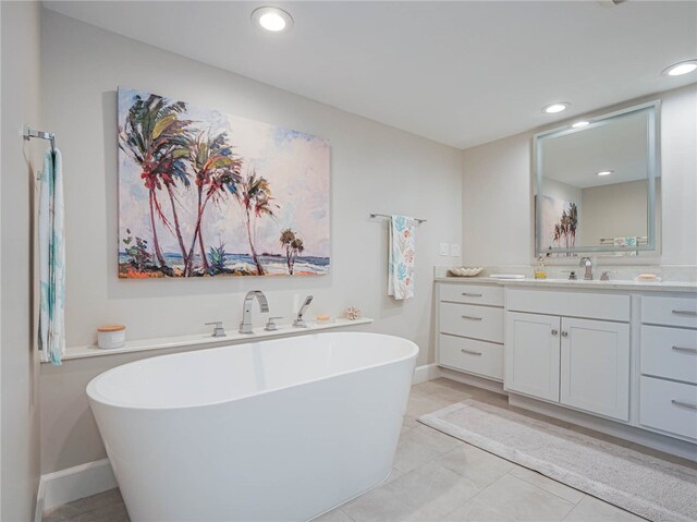 bathroom with a tub to relax in, vanity, and tile patterned floors