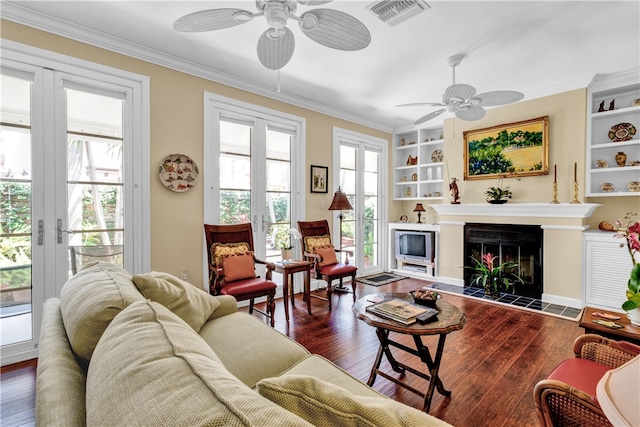 living room featuring dark hardwood / wood-style flooring, ornamental molding, ceiling fan, and built in shelves