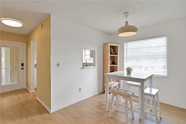 dining space featuring light hardwood / wood-style flooring and a textured ceiling