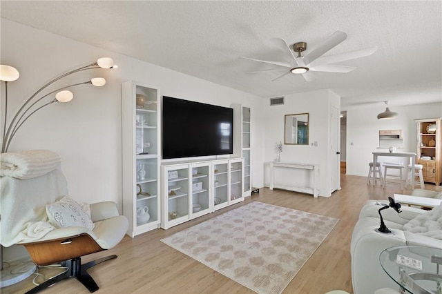 living room with ceiling fan, wood-type flooring, and a textured ceiling