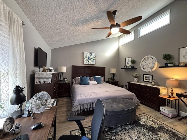 bedroom with ceiling fan, light hardwood / wood-style flooring, high vaulted ceiling, and a textured ceiling