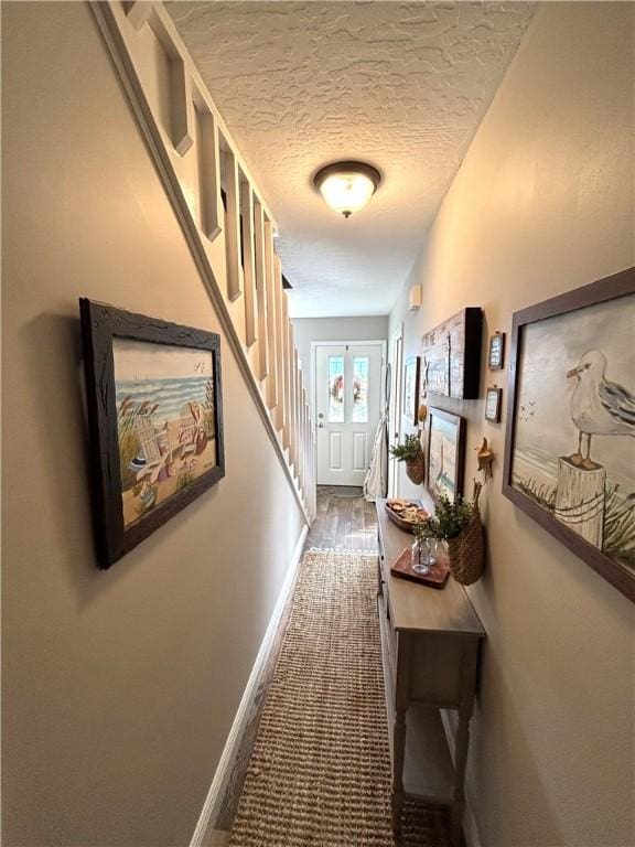 corridor featuring dark carpet and a textured ceiling