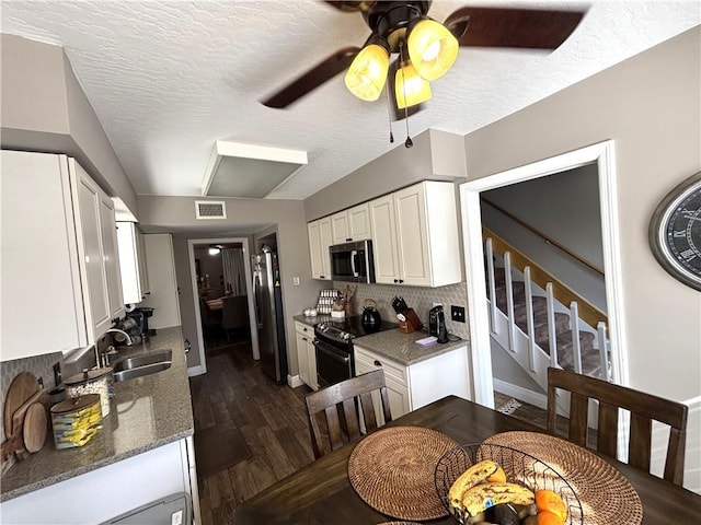 kitchen with stainless steel appliances, stone countertops, sink, and white cabinets