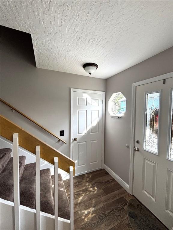 foyer entrance with dark wood-type flooring and a textured ceiling