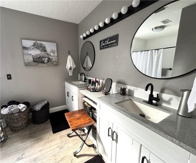 bathroom with vanity, wood-type flooring, and a textured ceiling