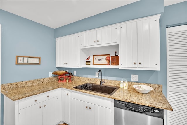 kitchen with light stone countertops, white cabinetry, sink, and stainless steel dishwasher