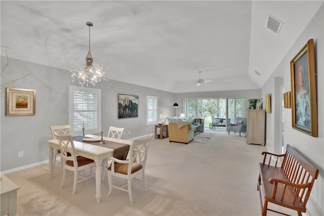 carpeted dining room featuring ceiling fan with notable chandelier and vaulted ceiling