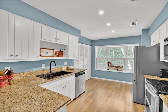 kitchen with white cabinets, appliances with stainless steel finishes, light hardwood / wood-style floors, and sink