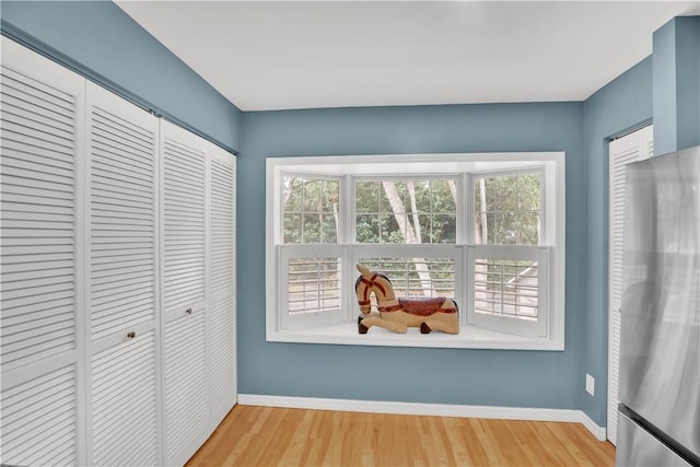 103 W Park Shores Cir Unit 10W, Vero Beach, FL 32963 - unfurnished bedroom with freestanding refrigerator, multiple windows, baseboards, and wood finished floors