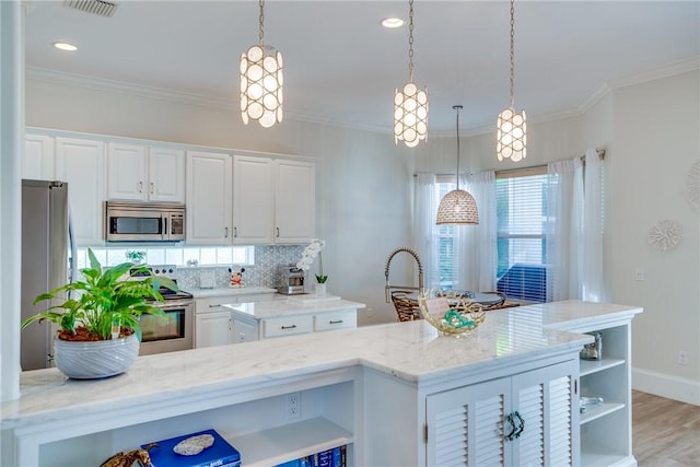 kitchen with white cabinets, appliances with stainless steel finishes, and hanging light fixtures