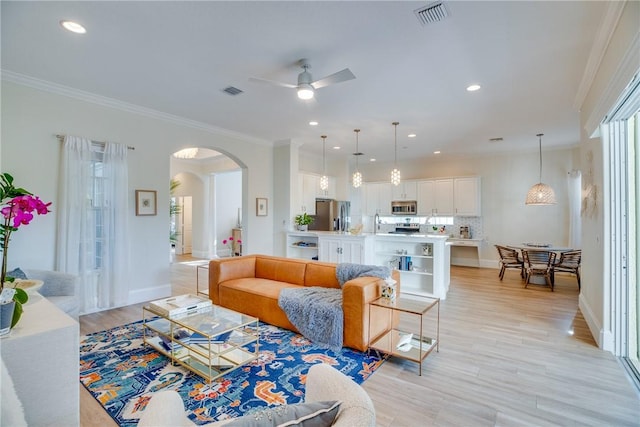 living room featuring ceiling fan, light hardwood / wood-style flooring, sink, and ornamental molding