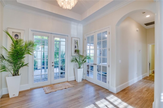 doorway featuring french doors, light wood-type flooring, crown molding, and a notable chandelier