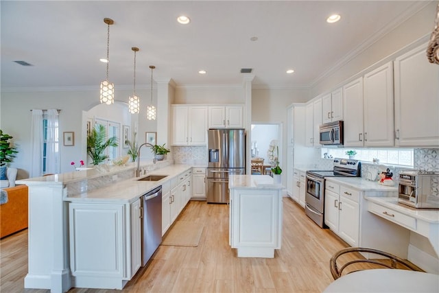 kitchen featuring sink, kitchen peninsula, light hardwood / wood-style floors, decorative light fixtures, and appliances with stainless steel finishes