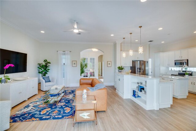 living room with light hardwood / wood-style floors, ceiling fan, and ornamental molding