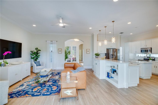 living room featuring ceiling fan, light wood-type flooring, and crown molding