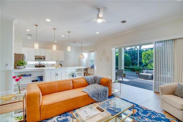 living room with ceiling fan, crown molding, and light hardwood / wood-style flooring