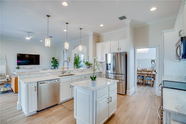 kitchen featuring white cabinets, sink, a center island, and appliances with stainless steel finishes