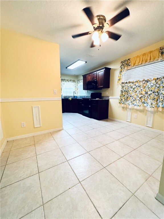 kitchen featuring a textured ceiling, ceiling fan, light tile patterned floors, and sink