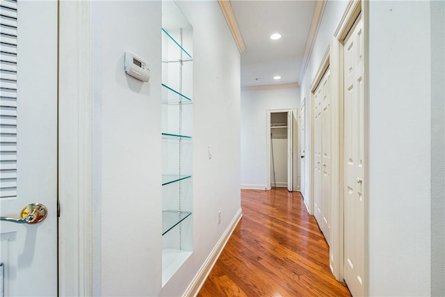 hallway with ornamental molding and hardwood / wood-style flooring