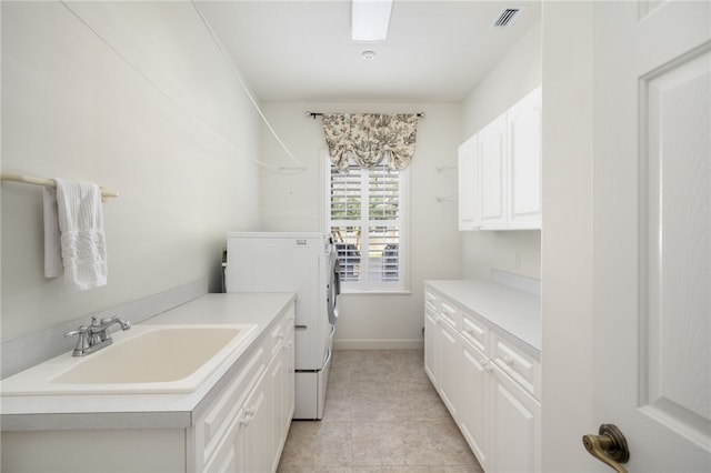 laundry room with light tile patterned flooring, cabinets, washer and clothes dryer, and sink