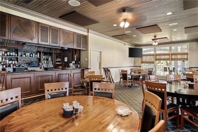 dining area featuring ornamental molding, carpet flooring, wooden ceiling, and ceiling fan