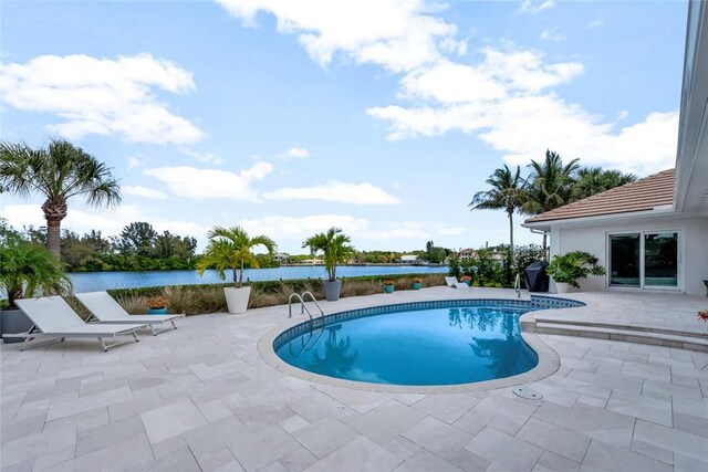 outdoor pool featuring a water view and a patio area