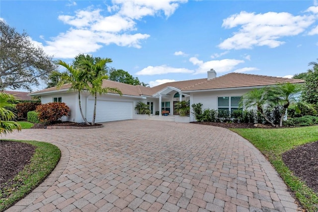 single story home featuring stucco siding, decorative driveway, a garage, a chimney, and a tiled roof