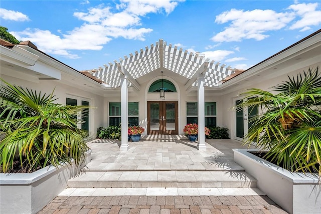 entrance to property with stucco siding, french doors, and a pergola