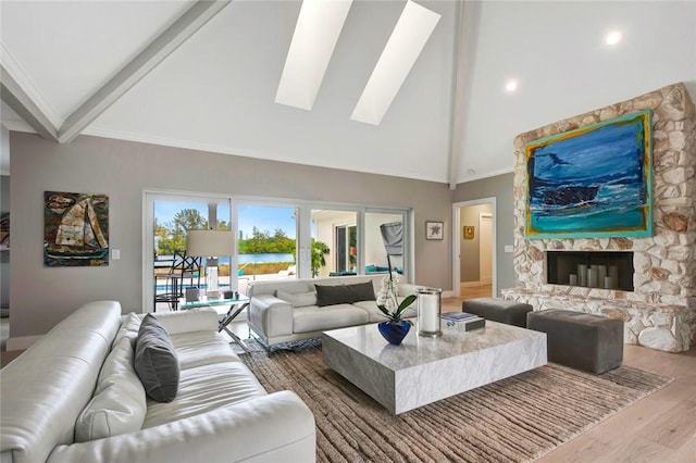 living room with beamed ceiling, high vaulted ceiling, wood finished floors, a skylight, and a fireplace