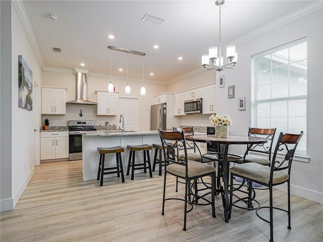 dining room with ornamental molding, sink, a chandelier, and light hardwood / wood-style floors