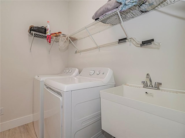 laundry room featuring sink, washer and clothes dryer, and light hardwood / wood-style floors