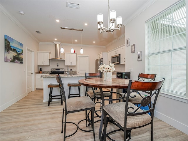 dining area featuring crown molding, an inviting chandelier, and light wood-type flooring