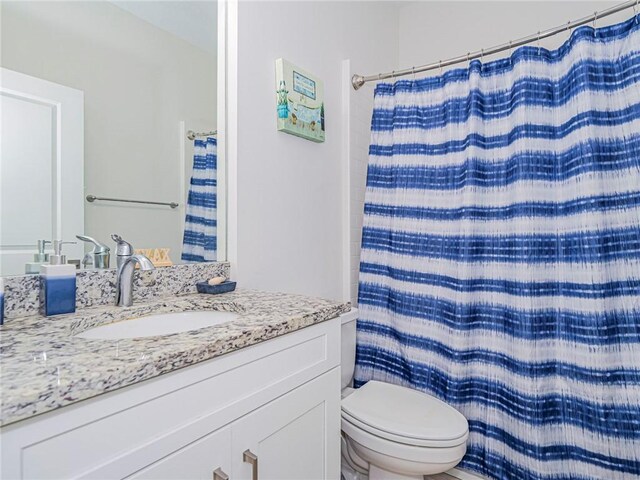 bathroom with walk in shower, vanity, and toilet