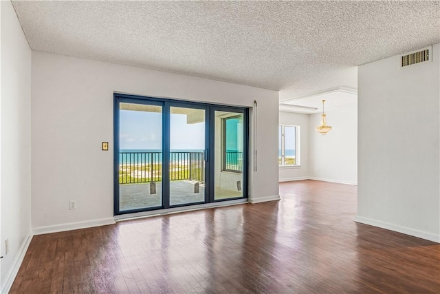empty room with wood finished floors, a textured ceiling, and baseboards