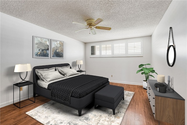 bedroom featuring a textured ceiling, wood finished floors, baseboards, and a ceiling fan
